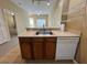 Kitchen shot with stainless steel sink, wood cabinetry, white dishwasher and easy access to the living area at 4010 Santa Maria Dr # 106, Kissimmee, FL 34741