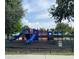Community playground with blue slides and red and blue play structure enclosed by fence at 4010 Santa Maria Dr # 106, Kissimmee, FL 34741