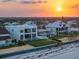 Aerial view showcases an elegant beach home with a private pool at sunset at 4647 Van Kleeck Dr, New Smyrna Beach, FL 32169