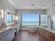 Bright and modern bathroom with a soaking tub overlooking the ocean, dual vanities, and a glass-enclosed shower at 4647 Van Kleeck Dr, New Smyrna Beach, FL 32169