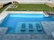 Aerial view of a private pool with in-water seating and a lush green lawn, perfect for outdoor relaxation and entertainment at 4647 Van Kleeck Dr, New Smyrna Beach, FL 32169