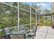 Enclosed patio area with clear glass table, comfortable chairs and a serene view of the garden at 468 Alinole Loop, Lake Mary, FL 32746