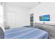 Bright bedroom featuring a large bed, closet, and TV with a tropical beach scene at 518 Marcello Blvd, Kissimmee, FL 34746