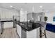 Open kitchen with a large island with black granite countertop, stainless steel appliances and gray chairs at 518 Marcello Blvd, Kissimmee, FL 34746