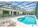 Screened-in pool and jacuzzi with lounge chairs and view of the home's rear exterior at 518 Marcello Blvd, Kissimmee, FL 34746