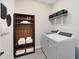 This home's laundry room has tile flooring, a storage cabinet, shelving, and a modern washer and dryer set at 5512 Settlingstone Ln, St Cloud, FL 34771