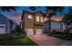 Inviting two-story home with a brick driveway, manicured landscaping and attached two-car garage at 7411 Excitement Dr, Reunion, FL 34747