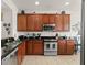 Modern kitchen featuring stainless steel appliances, granite countertops, and tile flooring at 7754 Teascone Blvd, Kissimmee, FL 34747