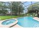 Relaxing screened-in pool and spa with a spacious patio and lush backyard view at 7754 Teascone Blvd, Kissimmee, FL 34747
