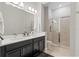 Bathroom featuring double vanity, large mirror, and tiled shower with glass doors at 7974 Chilton Dr, Orlando, FL 32836