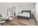Bedroom featuring wood-look floors, gray upholstered bed frame, chair, and large mirror at 7974 Chilton Dr, Orlando, FL 32836