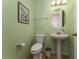 Charming powder room with green walls, a pedestal sink, and framed artwork at 9348 Meadow Hunt Way, Winter Garden, FL 34787