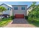 Two story home featuring a red two car garage door, brick paved driveway, and landscaped yard at 9348 Meadow Hunt Way, Winter Garden, FL 34787