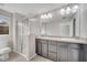Well-lit bathroom with double sinks, dark cabinets, and a glass-enclosed shower at 9559 Silver Buttonwood St, Orlando, FL 32832