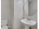 Simple bathroom featuring a pedestal sink, round mirror, and toilet, offering a functional and clean space at 9559 Silver Buttonwood St, Orlando, FL 32832