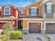 Inviting exterior showcasing a well-maintained multi-colored townhome with an attached garage and mature landscaping at 9559 Silver Buttonwood St, Orlando, FL 32832