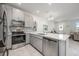 Well-lit kitchen featuring gray cabinetry, stainless steel appliances, quartz countertops and an open dining area at 10221 Highline Crest St, Orlando, FL 32832