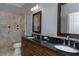 Bathroom with double sink vanity, granite countertop, dark wood cabinets, and walk-in shower with tile surround at 104 Forest Point Ln, Longwood, FL 32779