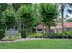 Landscaped entrance to the neighborhood with a sign, green lawn, and mature trees at 104 Forest Point Ln, Longwood, FL 32779