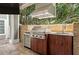 Outdoor kitchen area with cabinets, stone backsplash, built in grill, and stainless steel hood at 104 Forest Point Ln, Longwood, FL 32779
