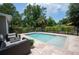 A beautiful backyard pool area with patio furniture and travertine tile, surrounded by lush landscaping at 104 Forest Point Ln, Longwood, FL 32779