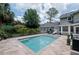 A backyard pool area with travertine tile, surrounded by lush landscaping and a black metal fence at 104 Forest Point Ln, Longwood, FL 32779