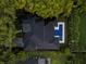 Aerial view of a luxury home with a dark roof, bordered by lush trees, with a blue pool and spa in the backyard at 1211 Munster St, Orlando, FL 32803