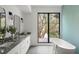 Bright bathroom featuring double vanity, soaking tub, large window with serene backyard views, and modern finishes at 1211 Munster St, Orlando, FL 32803