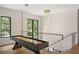 Hallway view of the glass railing, modern chandelier, and the shuffleboard table in the home at 1211 Munster St, Orlando, FL 32803