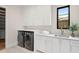 Well-lit laundry room featuring modern washer/dryer, ample counter space, and sleek white cabinetry at 1211 Munster St, Orlando, FL 32803