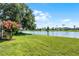Serene backyard view featuring a tranquil lake, lush green lawn, and mature trees at 14377 Lord Barclay Dr, Orlando, FL 32837