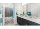 Bathroom with a dual-sink vanity and modern fixtures, plus a shower-tub combo with stylish blue curtain at 14880 Ellingsworth Ln, Winter Garden, FL 34787