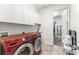 Laundry room with modern red Samsung washer and dryer, white cabinets, sink, and view to walk-in closet at 14880 Ellingsworth Ln, Winter Garden, FL 34787