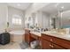 Bathroom featuring double vanities, large mirrors, arched window, and soaking tub at 16108 Bristol Lake Cir, Orlando, FL 32828
