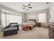Spacious bedroom with a large window, ceiling fan, ottoman, and dark wood furniture at 16108 Bristol Lake Cir, Orlando, FL 32828