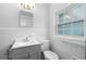 Bright bathroom featuring a gray vanity, white toilet, and a window for natural light at 1805 Paloma Ave, Sanford, FL 32771