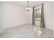 Bright dining room with contemporary chandelier, large window with gray curtains, and marble-look tile flooring at 2060 Panoramic Cir, Apopka, FL 32703