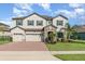 Elegant home with a three-car garage, stone-accented entrance, and verdant landscaping for enhanced curb appeal at 2060 Panoramic Cir, Apopka, FL 32703