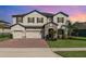 Stunning two-story home showcasing a three-car garage, stone accents, and a well-manicured lawn at 2060 Panoramic Cir, Apopka, FL 32703