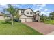 Beautiful home features a three-car garage, complemented by lush landscaping and a brick driveway at 2060 Panoramic Cir, Apopka, FL 32703