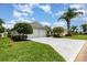 A well-maintained home exterior with a spacious driveway, mature trees, and manicured landscaping at 2135 Springwater Ln, Port Orange, FL 32128