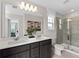 Bright bathroom featuring double sinks, tile flooring, a glass-enclosed shower, and a large mirror at 2241 Southbury Dr, Kissimmee, FL 34744