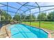 Screened-in pool area featuring a clear blue pool, lounge chairs, and a green lawn at 235 Aidans Lndg, Haines City, FL 33844