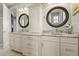 Bathroom featuring a double vanity with granite countertops, white cabinetry and decorative mirrors at 291 River Rd, Oak Hill, FL 32759