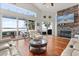 Living room with stone fireplace, wood floors, and large windows overlooking the water at 291 River Rd, Oak Hill, FL 32759