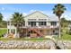 View of the rear exterior featuring a wooden deck, stairs to the water, and mature landscaping at 291 River Rd, Oak Hill, FL 32759