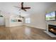 Open-concept living room with a fireplace, wood floors, a ceiling fan, and lots of natural light at 3055 Dellcrest Pl, Lake Mary, FL 32746