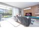 Living room with a gray sofa, television, and sliding glass doors leading to a screened-in pool area at 4414 Le Reve Ct, Kissimmee, FL 34746