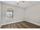 A clean, light-filled bedroom has wood-look floors and a window at 4870 S Semoran Blvd # 1905, Orlando, FL 32822
