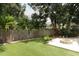 Fenced backyard featuring a fire pit, synthetic lawn, and mature trees at 5165 Mystic Point Ct, Orlando, FL 32812